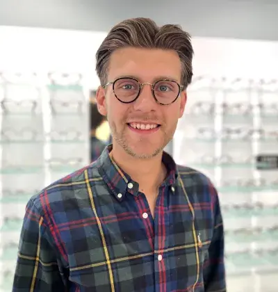 Portrett av optikerassistent Johann Karlsen Bjørseth foran en brillevegg
