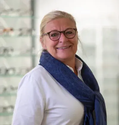 Portrett av optikerassistent Randi Støyten Bjørseth foran en brillevegg