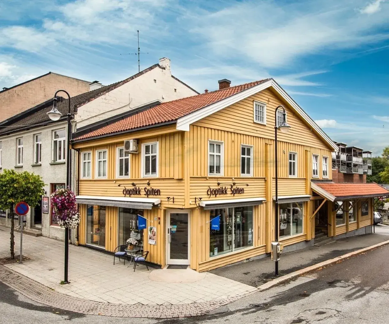Den gule hjørnegården i Storgata 20 på Kongsberg med c)optikk Spiten-skilt